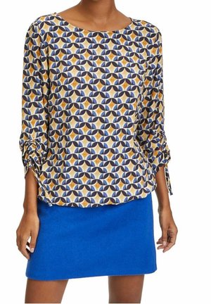 Multifarvet mønsterbluse med trekvartærmer, der har en rund halsudskæring og samlede manchetter. Kombineret med en blå filt mini-sund.