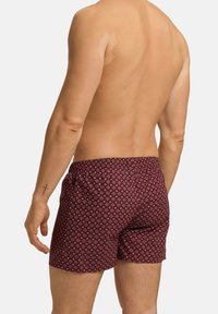 Shorts de bain pour hommes dans une teinte bordeaux avec un motif géométrique. Dotés d'une taille élastique et d'une coupe décontractée pour un maximum de confort.