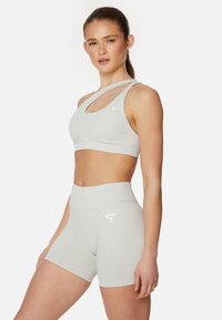 Lichtgrijs sport-bh en hooggeplaatste short-set, met een uitsnijd ontwerp, gladde textuur en een witte logo-accent op elk stuk.