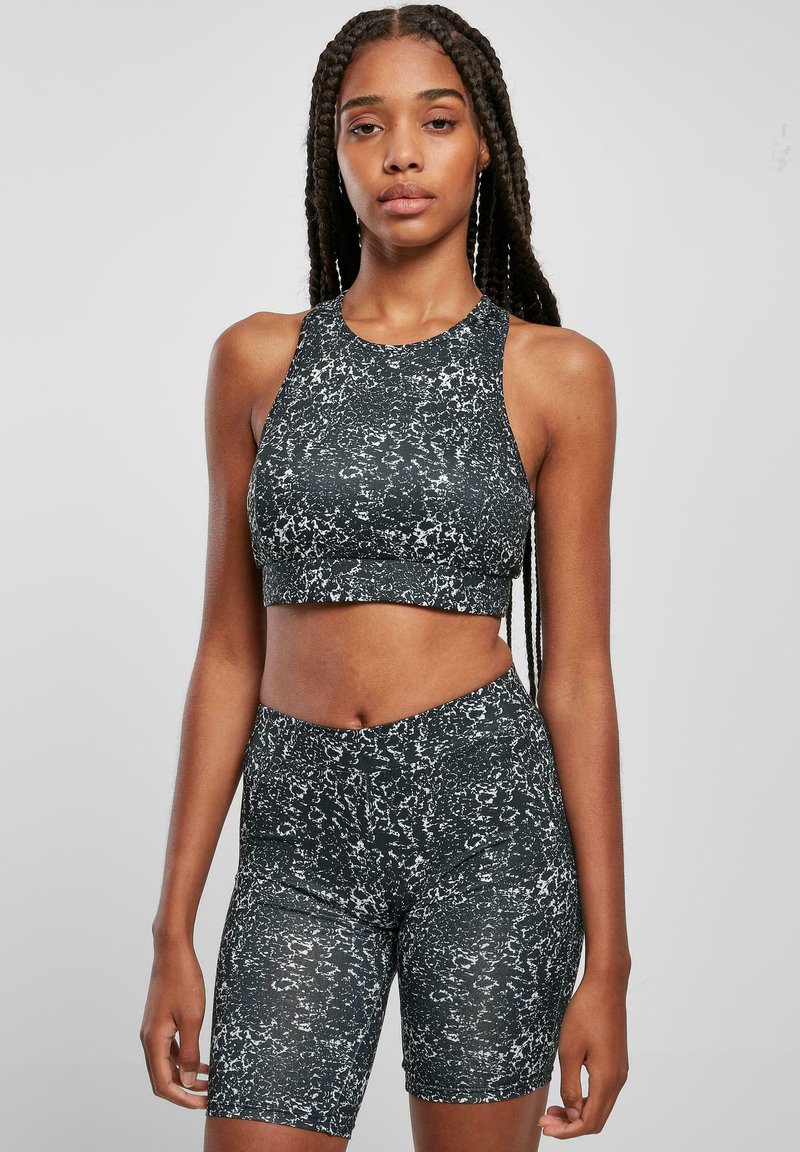 Svart- och vitmarblerad sportuppsättning med en ärmlös crop top och högmidjade shorts, tillverkad av stretchigt, texturerat tyg.