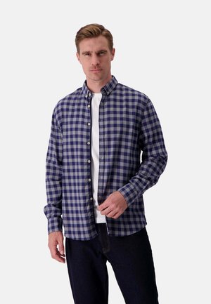 Karobluse in Marineblau und Grau mit Kragen, langen Ärmeln und geradem Saum, darüber getragen mit einem weißen Rundhalsausschnitt-T-Shirt.