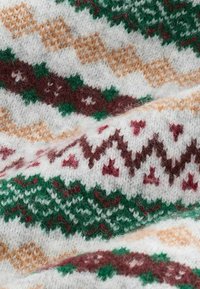 Knitted sweater fabric featuring a patterned design with green, brown, and tan diamonds, zigzags, and stars on a white background.