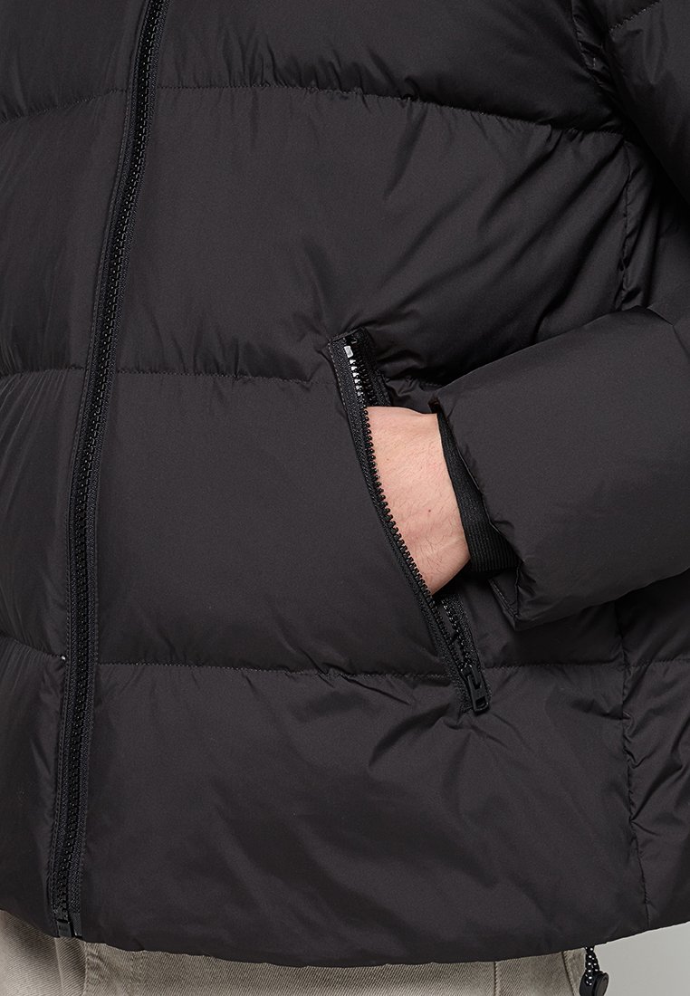 Schwarze Daunenjacke mit horizontalen Nähten, einem durchgehenden Reißverschluss und einer seitlichen Reißverschlusstasche. Glattes, isoliertes Material mit matter Oberfläche.