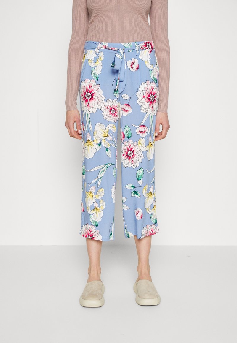 Pantaloni floreali azzurri con vita regolabile, caratterizzati da grandi fantasie floreali rosa e gialle e dalla lunghezza cropped. Tessuto di consistenza liscia.