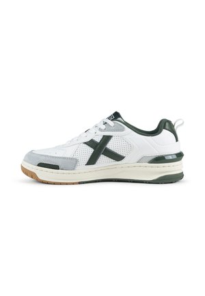 Zapatilla deportiva blanca y gris de caña baja con detalles en verde oscuro, paneles laterales perforados y una suela beige y crema vista desde el lado exterior.