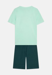 Ανοιχτό πράσινο κοντομάνικο μπλουζάκι συνδυασμένο με σκούρο πράσινο σορτσάκι. Και τα δύο κατασκευασμένα από μαλακό βαμβάκι με απλό, χωρίς ραφές σχέδιο.