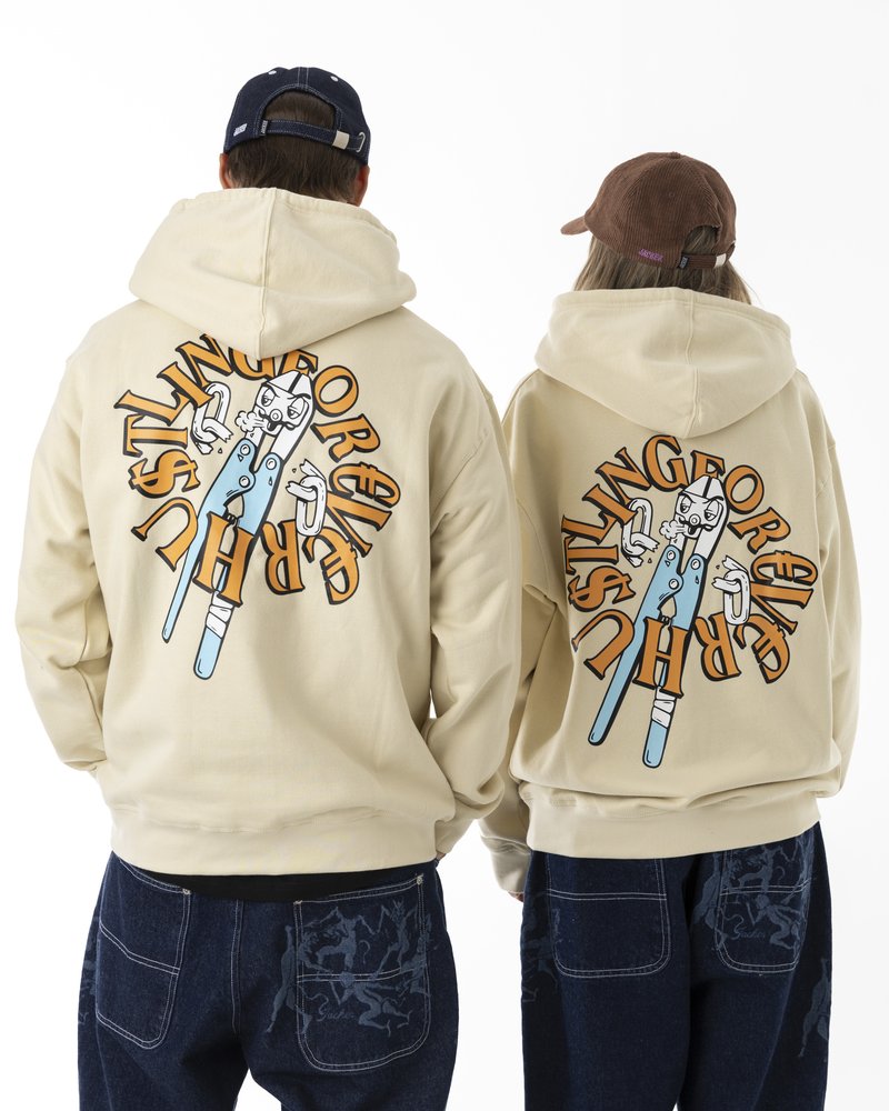 Kremfargede hettegensere har store grafiske design på ryggen med en tegneseriefigur og tekst i oransje og svart. Dongeribukser har kontrasterende søm.