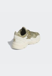 Olivgrön och krämfärgad sneaker med texturerad ovandel, rund tå och en framträdande klack. Har ton-i-ton sömmar och logotypdetalj.