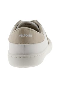 Zapatilla de cuero blanca con acentos beiges, punta redonda, talón acolchado y paneles laterales texturizados. Presenta el logotipo "victoria" en el talón.