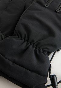 Guanti isolanti neri con polsini elastici, tessuto liscio, coulisse regolabile e cuciture rinforzate lungo le cuciture.