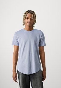 Lichtblauw T-shirt met korte mouwen en een ronde zoom, gemaakt van een zachte stof. Draagt bij donkere jeans, met een eenvoudig ontwerp zonder patronen.