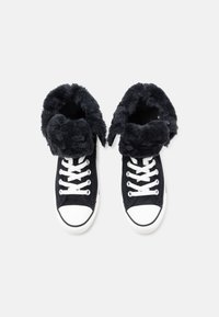 Zapatillas altas negras con un puño esponjoso, cordones blancos y puntera de goma. Textura suave y material duradero. Diseño clásico con acentos en contraste.