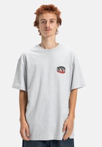 Šedé bavlněné tričko s krátkým rukávem, které na levé části hrudi má multicolorní grafické logo a volnější střih.