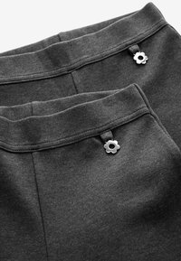 Graue Baumwollhose mit glatter Textur. Verfügt über einen breiten Bund und eine silberne, blumenförmige Hardware-Akzentuierung auf der Vorderseite.