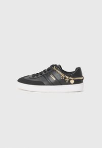 Svart sneaker laget av lær og tekstil, med hvit såle, gullkjede-detaljer og logo på siden.