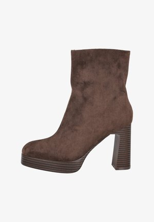 Botín de ante marrón hasta el tobillo con un alto tacón cuadrado, punta redonda y suela de plataforma. El tacón presenta una textura de madera a rayas.