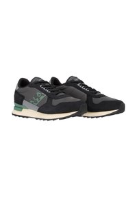Zapatillas deportivas negras que presentan una combinación de materiales de ante y malla, con acentos verdes y una suela de goma texturizada con un patrón en zigzag.