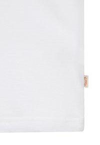 Tissu blanc avec une petite étiquette beige sur le bord droit comportant un texte orange dans un design plié.