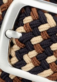 W plecionym pasku z mieszanką ciemnoniebieskich, brązowych i beżowych włókien; posiada srebrną metalową klamrę i teksturowany, pleciony wzór.