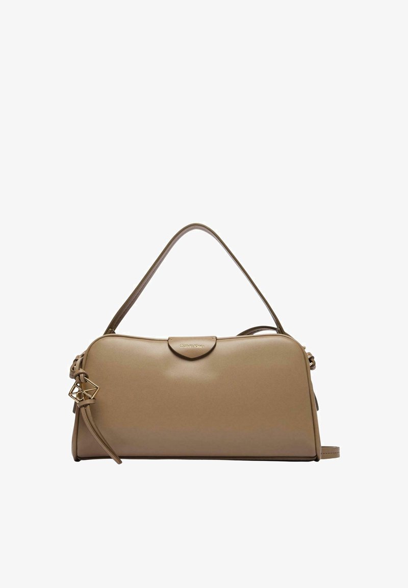Sac à main en cuir beige avec une seule poignée supérieure, un pendentif géométrique doré et un logo Calvin Klein discret sur un rabat de fermeture.