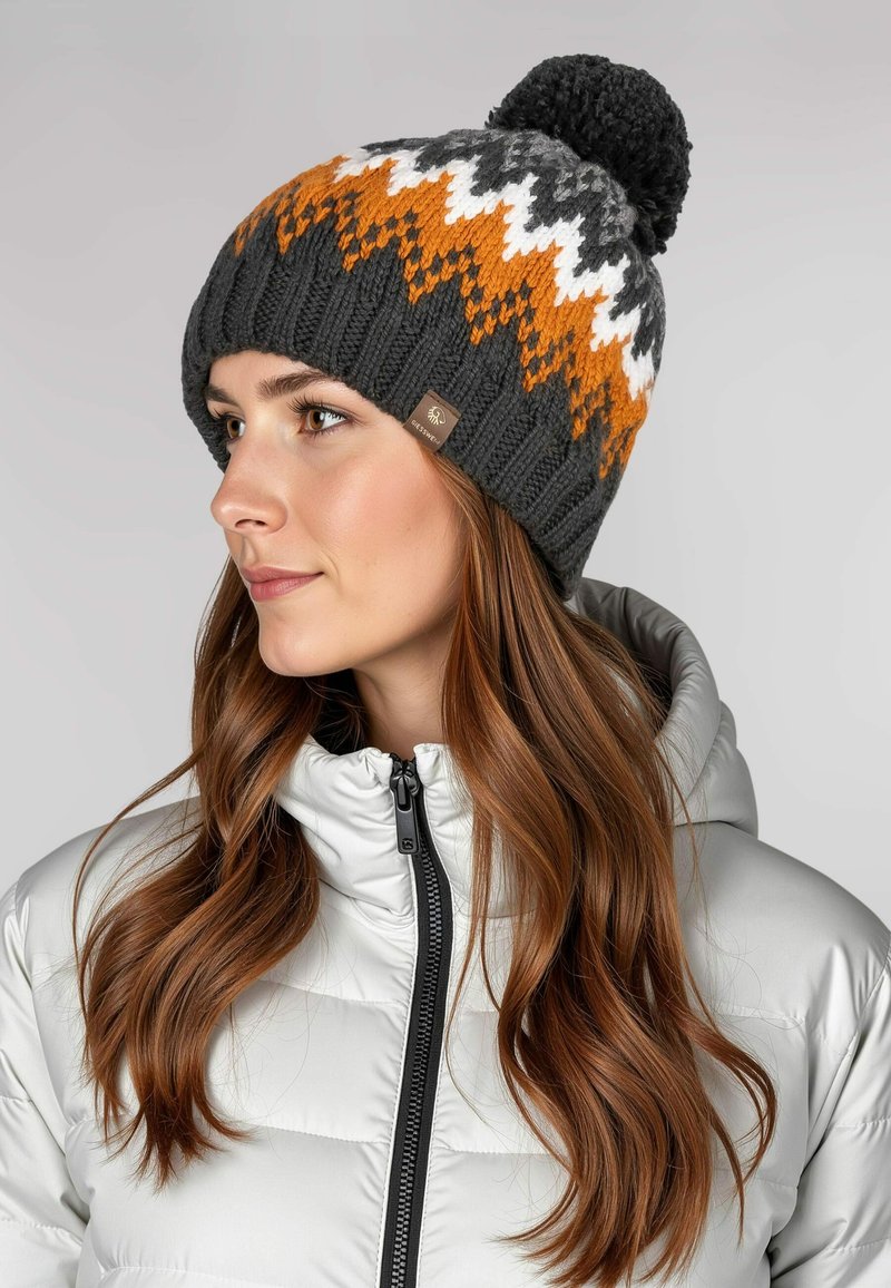 Gehaakte muts met een grijze basis, voorzien van oranje, witte en donkergrijze zigzagpatronen; afgewerkt met een zwart pompon. Inclusief een merketiket.