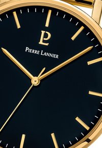 Reloj de pulsera de tono dorado con un dial negro, que cuenta con marcadores de hora y manecillas doradas. Logotipo de "Pierre Lannier" situado por encima del centro.
