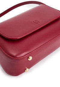 Borsa in pelle rossa con chiusura a patta, logo impresso, tracolla sottile e due piedini in metallo dorato sul fondo.