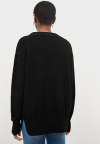 Sort oversized sweater med en struktureret finish, der har en bred krave og ribbet kant. Bagsiden er lidt længere med sideslidser.
