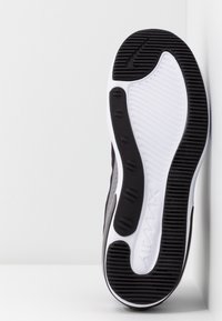 Black and white athletic shoe sole with textured rubber, featuring a curved design and visible Air Max branding. Smooth and ribbed patterns.