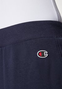 Mornarice plave kratke hlače od laganog pamuka s elastičnim pojasom i malim izvezenim logotipom s crvenim i belim akcentima na kuku.