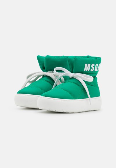 Botas de tecido acolchoado verde com colarinho acolchoado, atacadores brancos e sola branca grossa. Apresentam "MSG" impressa em branco no colarinho.