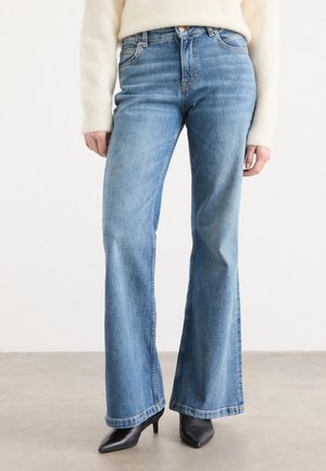 Lyseblå vide jeans laget av denim med høyt liv. Features inkluderer kontraststing og rå kant. Kombinert med svarte spisse hæler.