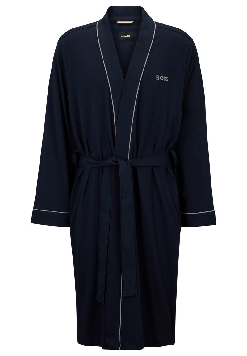 Marineblauw gewaad gemaakt van zacht stof. Beschikt over lange mouwen, een tailleband en lichtgrijze piping langs de randen. Inclusief logo op de borst.