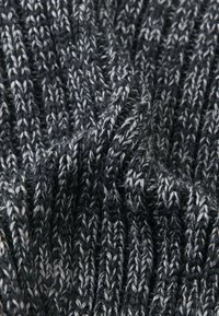 Tessuto lavorato a maglia con una texture a coste in tonalità grigio scuro e grigio chiaro, che mostra uno spessore variabile nei punti e un aspetto morbido.