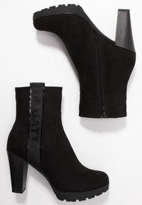 Botines de ante negro con tacón grueso texturizado, cremallera lateral y una correa de tela con la palabra "BUGATTI". Suela gruesa para tracción.