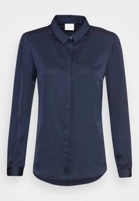 Maglietta a maniche lunghe blu navy realizzata in tessuto morbido, con colletto classico, chiusura con bottoni e spalle leggermente imbottite.