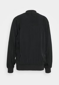 Černá bunda s dlouhým rukávem a vysokým límcem, s elastickými manžetami a lemem, zobrazená zezadu na bílém pozadí.