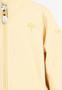 Geltona lietpaltis turi užtrauktuko uždarymą ir nedidelį siuvinėtą skėčio logotipą ant krūtinės. Minkšta tekstūra su sklandžiu paviršiumi.