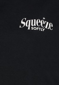 Schwarzer Baumwoll-Sweatshirt mit weißem Text, der "Squeeze Softly" liest, mit einem Sternakzent über dem 'i'. Einfaches, lässiges Design.