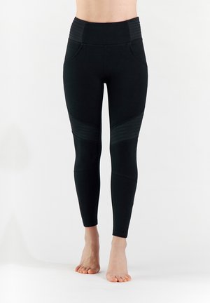 Leggings noirs avec une taille haute, des détails côtelés et des poches latérales, au design ajusté et en matière lisse et extensible.
