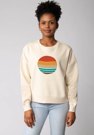 Crème sweatshirt met een ronde grafiek in oranje, geel en teal strepen. Beschikt over een losse pasvorm, geribbelde manchetten en een zachte textuur.