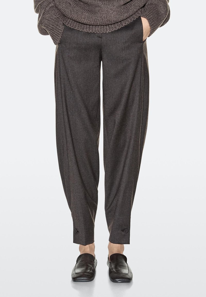 Pantaloni grigi su misura realizzati in tessuto morbido, caratterizzati da una vestibilità ampia, gambe larghe e tasche laterali; dettagliati con un motivo sottile ai polsini.