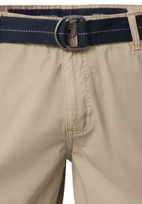 Beżowe szorty o gładkiej fakturze, z granatowym paskiem z okrągłą metalową klamrą i widocznymi detalami szwów.