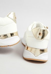 Vita sneakers med metalliska guldaccenter, med en texturerad läderöverdel, slät, böjd hälkappa och gummisula med bra grepp.