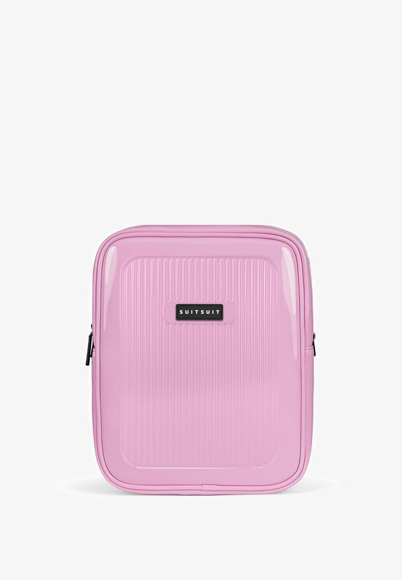 Pink hard-shell suitcase with vertical ridges, glossy texture, and a black logo patch. Features a zip closure and sleek rectangular design.