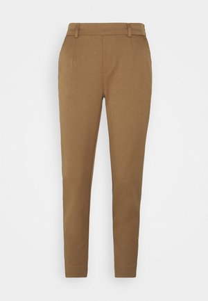 Pantalon slim couleur camel avec passants de ceinture, couture devant et jambes fuselées sur fond blanc uni.
