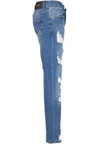 Jeans ajustados en denim azul claro con áreas desgastadas, que cuentan con una cinturilla alta, cinco bolsillos y una textura suave.