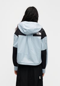 Ελαφρύς μπλε και μαύρος αδιάβροχος με κουκούλα, με λογότυπο στην πλάτη, ελαστικές μανσέτες και άνετη εφαρμογή.