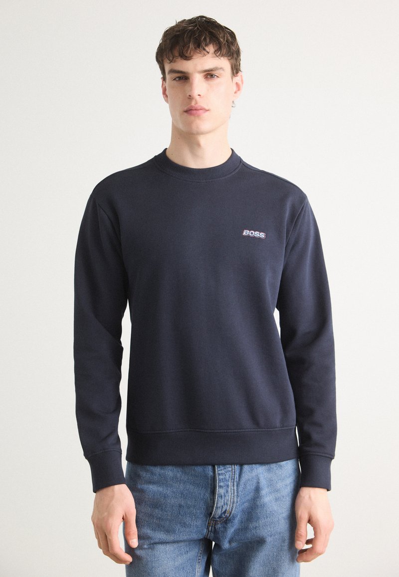 Sudadera azul marino en mezcla de algodón, con cuello redondo acanalado, mangas largas y un pequeño logotipo bordado en el pecho.