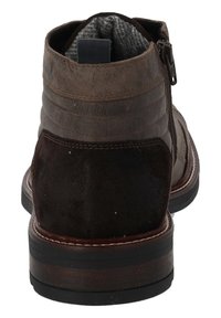 Botas de tobillo de cuero marrón con un acabado de gamuza texturizada, panel lateral elástico y una tira de tirón. Detalles de costura sutiles y una suela resistente.